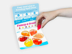 The 6-flavors hydrating Jelly Drops sample pack, with a hand holding a pink-colored drop.